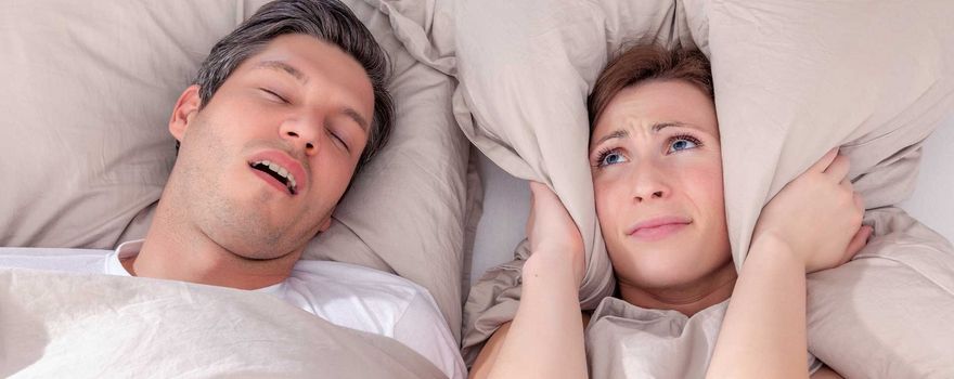 Frau und Mann liegen im Bett, da der Mann schnarcht kann Frau nicht schlafen.