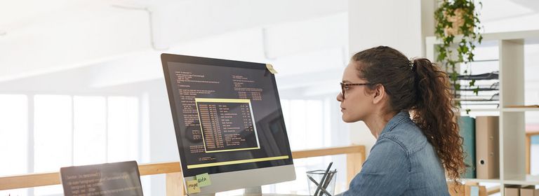 Junge Frau programmiert auf ihrem Computer in einem modernen Büro..