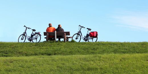 Ehepaar sitzt auf einer Bank neben Fahrrädern