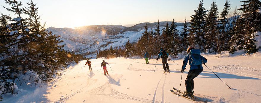 Skifahrer auf der Piste bei Sonnenuntergang mit Blick auf die verschneiten Berge
