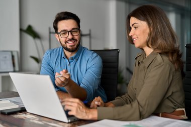 Zwei Personen sitzen vor einem Laptop