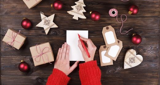 Frau schreibt Einkaufsliste für Weihnachtsgeschenke