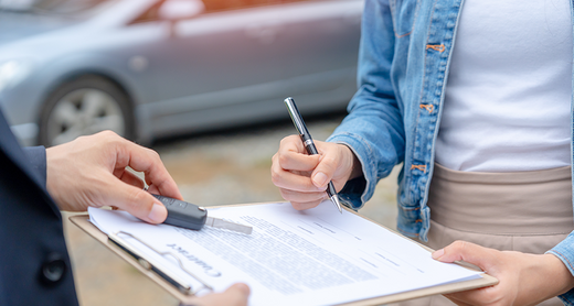 Frau unterschreibt einen Auto Kaufvertrag