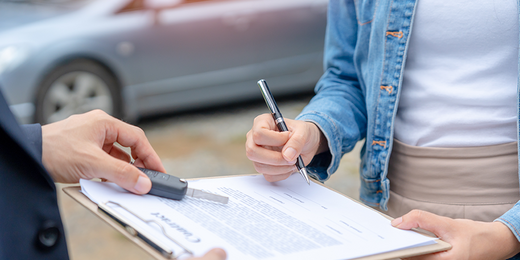 Frau unterschreibt einen Auto Kaufvertrag