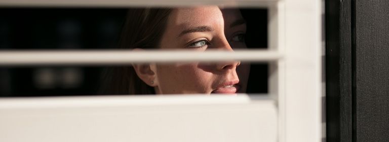 Frau schaut durch Fenster und stalkt eine Person