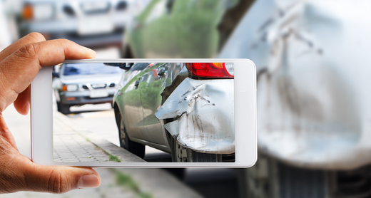 Person fotografiert Autoschaden nach Unfall mit dem Smartphone