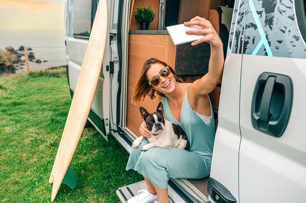 Eine junge Frau macht ein Selfie von sich und ihrem Hund in einem Wohnmobil