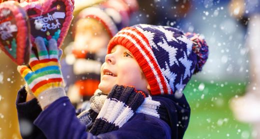 Kleiner Bub schaut Lebkuchenherz auf Weihnachtsmarkt an 
