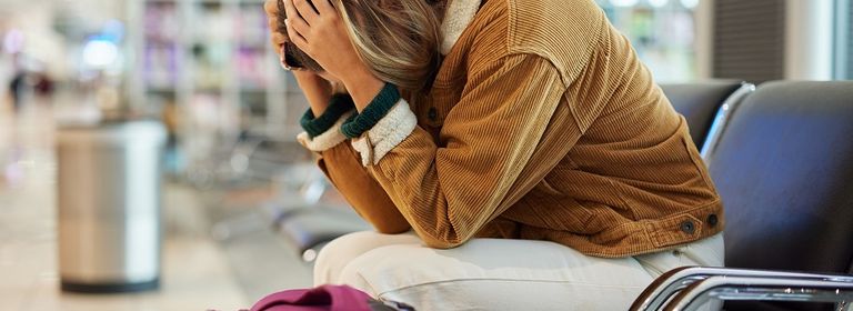 Frau sitzt verzweifelt am Flughafen