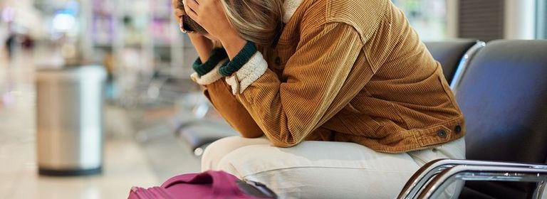 Frau sitzt verzweifelt am Flughafen