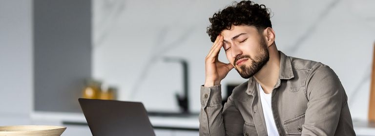 Mann sitzt am Laptop und zerbricht sich den Kopf aufgrund eines Gewerbeentzugsverfahrens