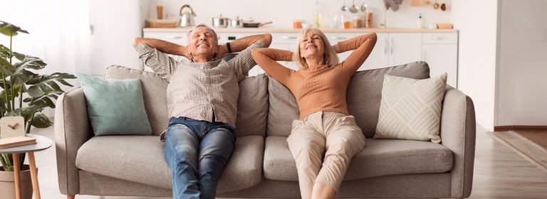 Älteres Paar lehnt sich auf Sofa zurück