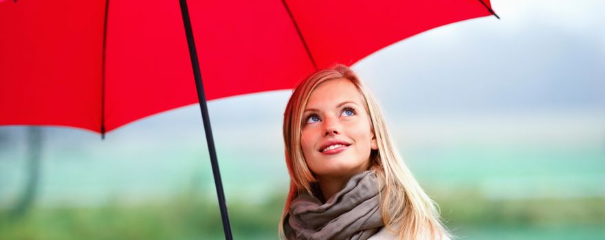 Junge blonde Frau mit rotem Regenschirm in der Hand