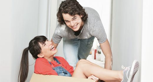 Frau und Mann lachen beim Umzugskarton packen. Wohnungswechsel - was passiert mit der Haushaltsversicherung?