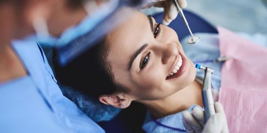 Frau beim Zahnarzt werden die Zähne poliert, um Zahnverfärbungen zu entfernen