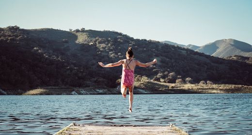 Mädchen springt von Steg ins Wasser