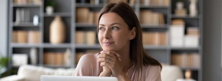 Frau sitzt im Wohnzimmer vor ihrem Laptop