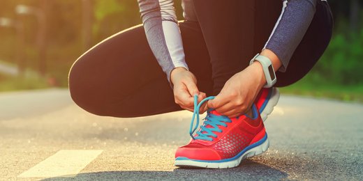 Frau bindet sich die Laufschuhe auf der Straße