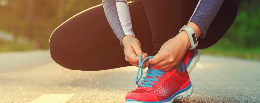 Frau bindet sich die Laufschuhe auf der Straße