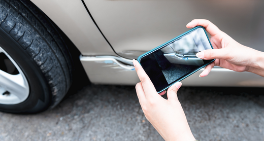 Person fotografiert einen Schaden am Auto mit dem Smartphone Person fotografiert einen Schaden am Auto mit dem Smartphone