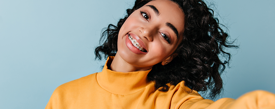 Selfie einer dunkelhaarigen jungen Frau mit gelben Pullover und weißen Zähnen 