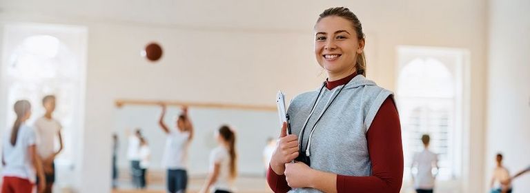 Trainerin einer Volleyballmannschaft steht am Rand des Spielfelds