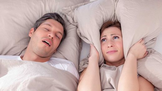 Frau und Mann liegen im Bett, da der Mann schnarcht kann Frau nicht schlafen.
