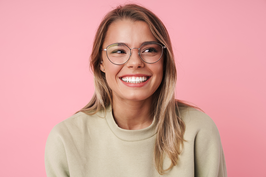 Junge Frau mit weißen Zähnen und Brille lächelt 