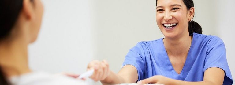 Krankenschwester gibt Patientin Unterlagen zum Unterschreiben