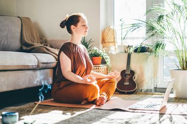 Junge Frau sitzt auf einer Yogamatte und meditiert