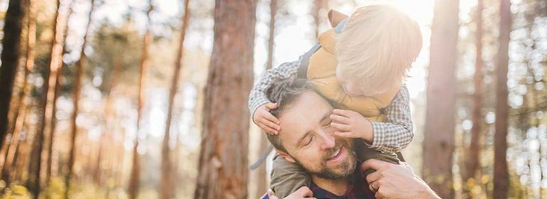 Vater trägt seinen Sohn auf den Schultern im Wald