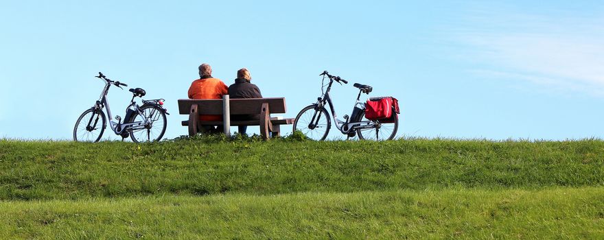 Ehepaar sitzt auf einer Bank neben Fahrrädern