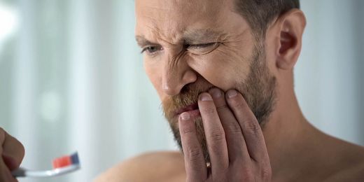 Mann hat Schmerzen aufgrund von Zahnfleischbluten