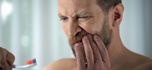 Mann hat Schmerzen aufgrund von Zahnfleischbluten
