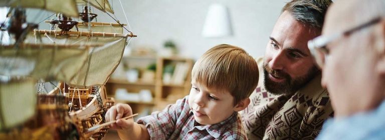 Großvater, Vater und Sohn spielen gemeinsam mit einem Modellschiff