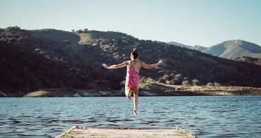 Mädchen springt von einem Steg in den See