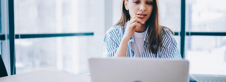 Frau sitzt am Laptop und führt einen Website Check durch