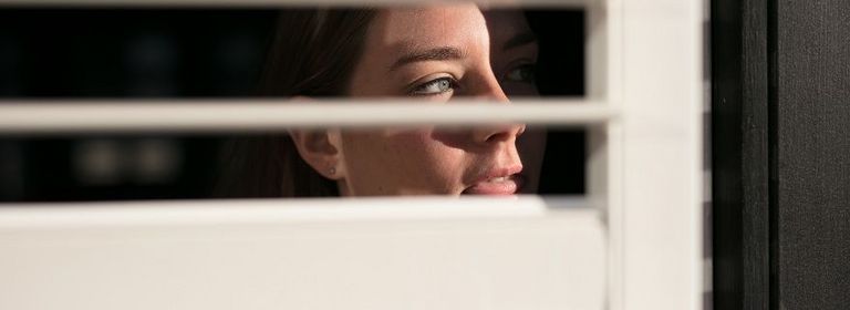 Frau schaut durch Fenster und stalkt eine Person