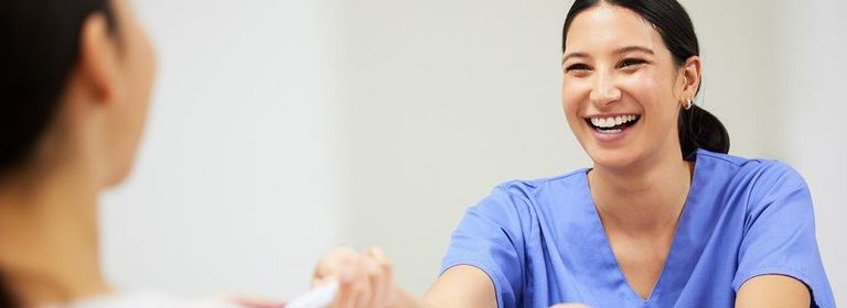 Krankenschwester gibt Patientin Unterlagen zum Unterschreiben
