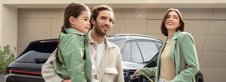 Familie steht vor schwarzem Elektroauto